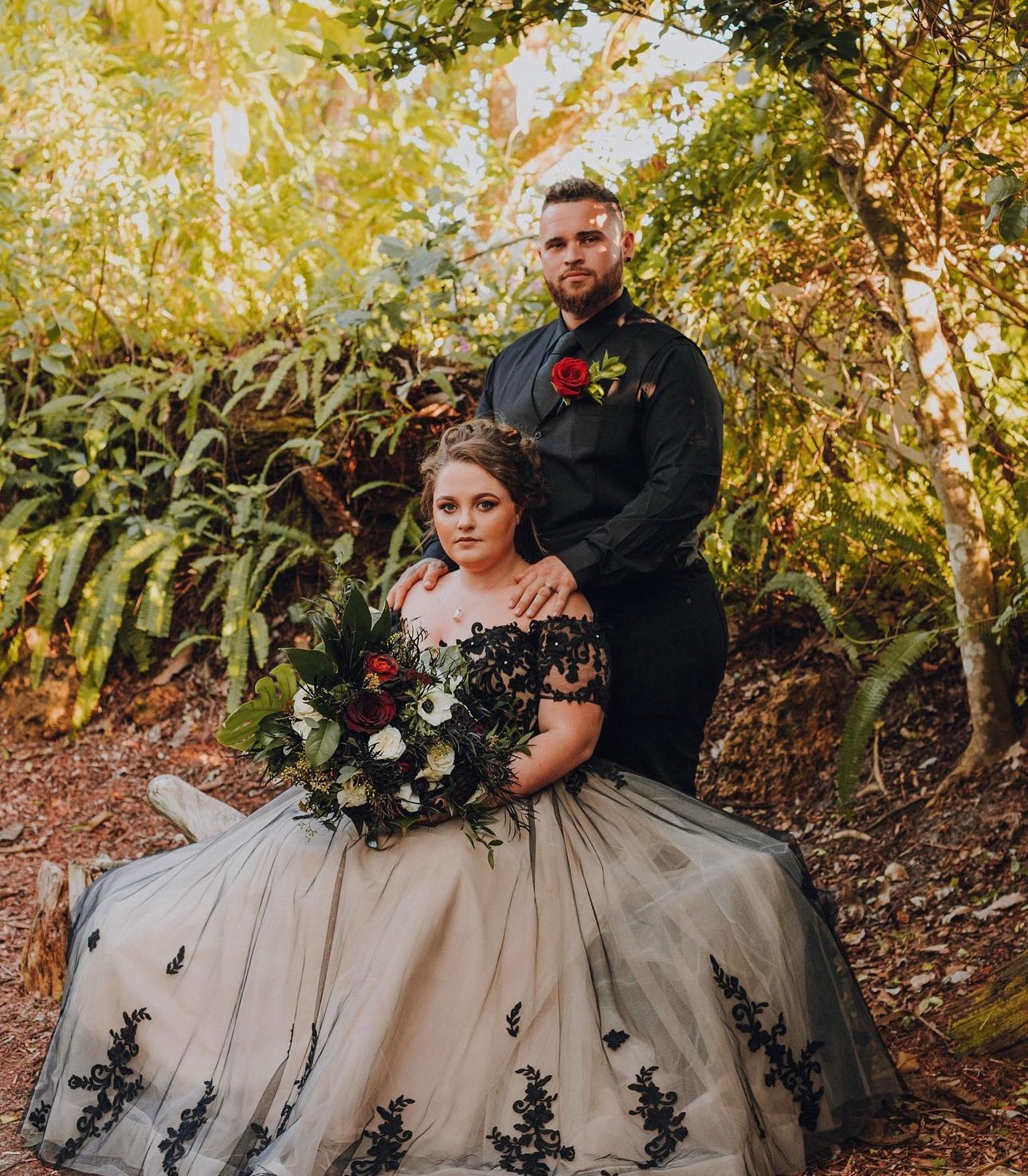 Bride and groom in a garden with a black and red wedding palette