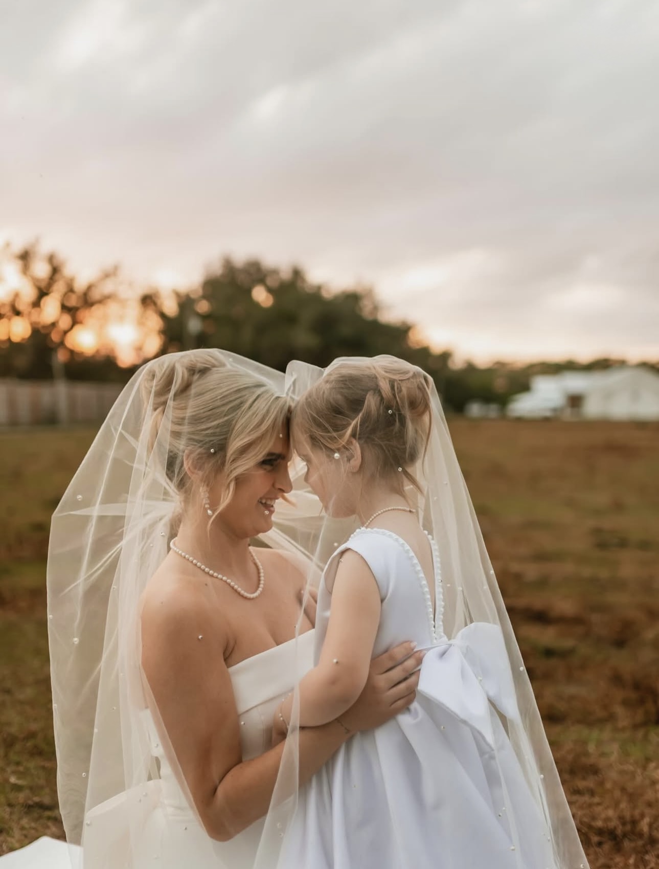 Bride and flower girl sharing a moment outdoors