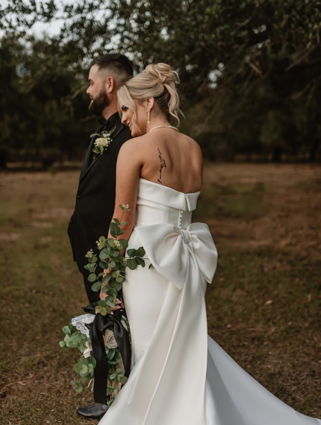 Bride and groom outdoors with her updo and bow detail